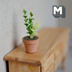 1:12 scale miniature potted leafy plant in clay pot, green upright stems, shown on a wood cabinet