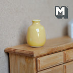 1:12 scale miniature yellow ceramic bud vase with glossy glaze and narrow neck, shown on a wood dresser