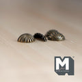 1:12 scale miniature half moon drawer pulls in antique brass, set of 4, ribbed shell shape, on a light wood surface