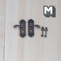 1:12 scale miniature door lever handles with backplates and keys in antique copper, set of 4, on a light wood surface