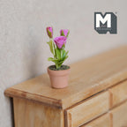 1:12 scale miniature potted pink roses with green leaves in a terracotta pot, shown on a wood dresser