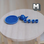 1:12 scale miniature blue ceramic teapot, 4 cups and round tray, set of 6, shown on a round wood table