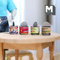1:12 scale miniature opened tin cans with colorful food labels and raised lids, set of 4, shown on a round wood table