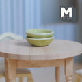 1:12 scale miniature pale green ceramic bowls, set of 2, shown stacked on a round wood table