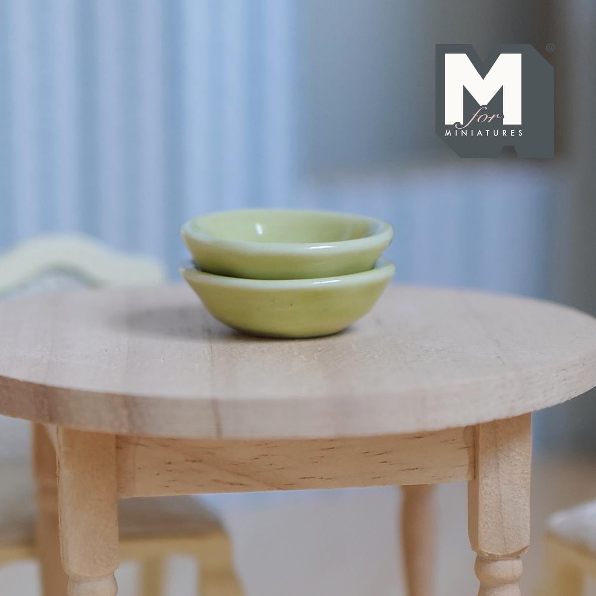 1:12 scale miniature pale green ceramic bowls, set of 2, shown stacked on a round wood table
