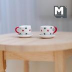 1:12 scale miniature ceramic cups and saucers with red and blue polka dots, set of 4, shown on a round wood table
