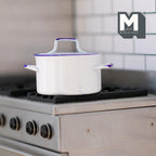 1:12 scale miniature enamel look metal cooking pot with lid in white with blue trim, shown on a silver stove