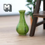 1:12 scale miniature ceramic pear shaped vase in glossy green with ribbed base and flared neck, on a wood floor