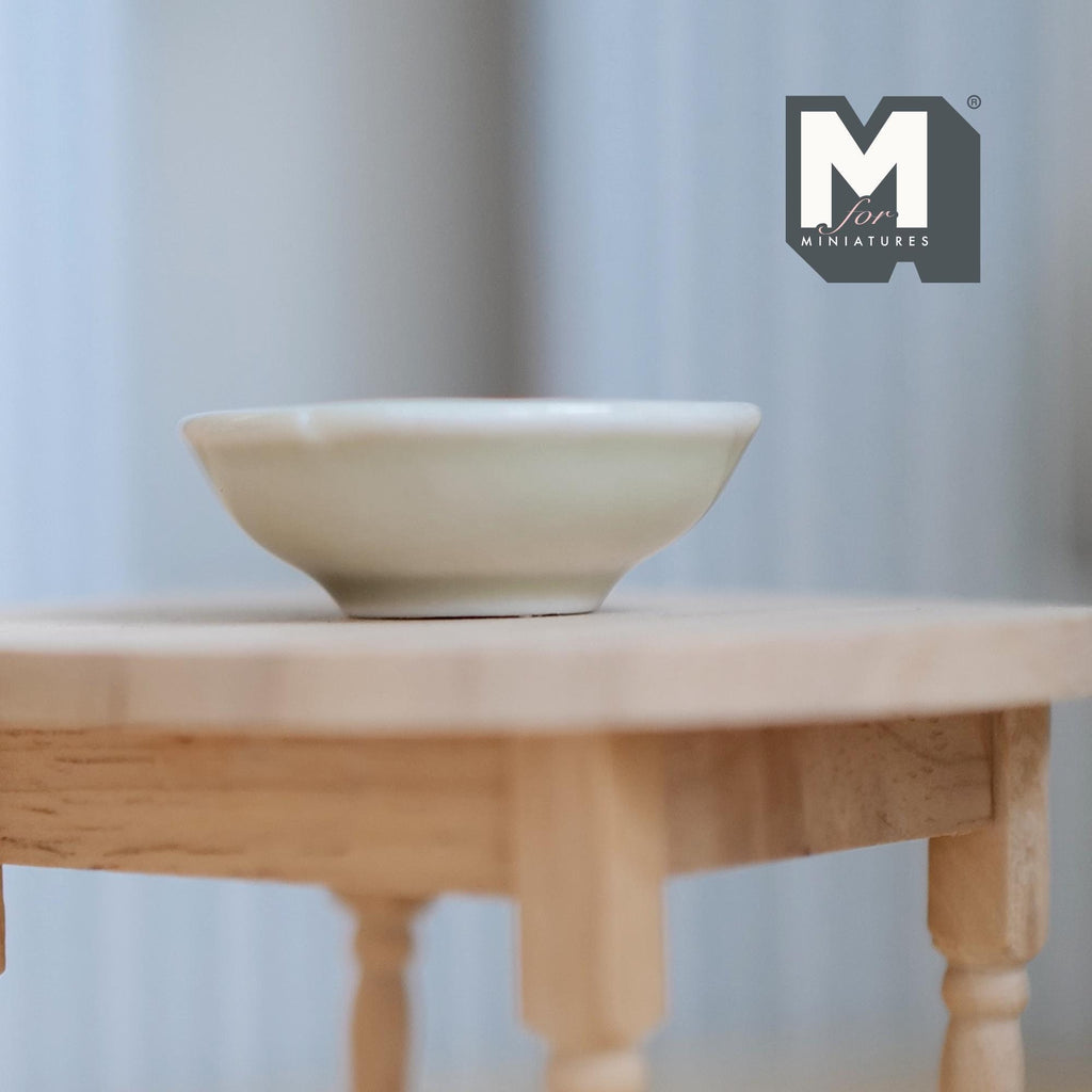 1:12 scale miniature large ceramic fruit bowl in light green with a wide rim, shown on a round wood table