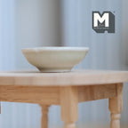 1:12 scale miniature large ceramic fruit bowl in light green with a wide rim, shown on a round wood table