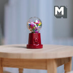 1:12 scale miniature metal tabletop gumball machine in red with colorful gumballs, non working, shown on a wood table