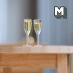 1:12 scale miniature champagne flutes with sparkling wine, set of 2, clear stems, shown on a round wood table