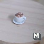 1:12 scale miniature latte coffee cup with saucer, white cup with latte art foam, shown on a round wood table