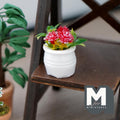 1:12 scale miniature potted flowering plant with red blooms and green leaves in a round white pot, shown on a dark wood shelf