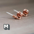1:12 scale miniature metal wall candle sconces in champagne with white candles, set of 2, lying on a wood surface