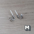 1:12 scale miniature metal wall candle sconces in silver with white candles, set of 2, lying on a wood surface