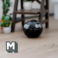 1:12 scale miniature black ceramic globular vase with white daisy pattern, large size, shown on a wood floor