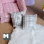 1:12 scale miniature fabric square cushions in gray plaid, set of 2, shown on a white fur rug by a pink armchair