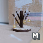 1:12 scale miniature wood cat tree with dark brown scratching posts, hanging ball toys and a round cream base