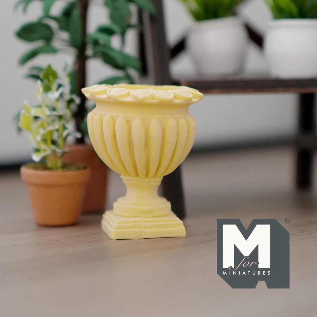 1:12 scale miniature Roman style pedestal urn vase in yellow cast resin with fluted sides, beside potted plants