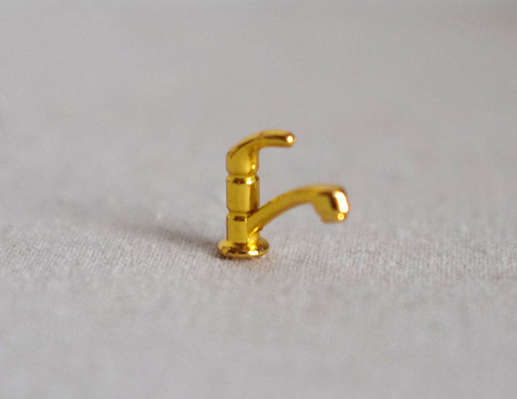 1:12 scale miniature single lever faucet in gold with a gooseneck spout, shown standing on a beige surface