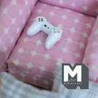 1:12 scale miniature white metal gaming controller, non working, shown on a pink polka dot sofa