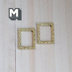1:12 scale miniature ornate picture frames in gold, set of 2, empty rectangular frames lying on a light wood surface
