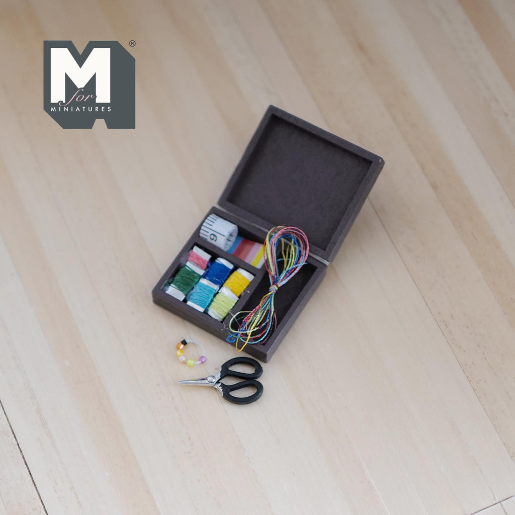 1:12 scale miniature dark brown wood needlework box with ribbons, thread and scissors, shown open on a light wood floor