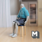 1:12 scale miniature round stool in dark blue with wood legs, shown with a jointed figure seated on it