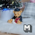 1:12 scale miniature resin bear cub figurine in navy sailor outfit holding a sail boat, on a white fur rug