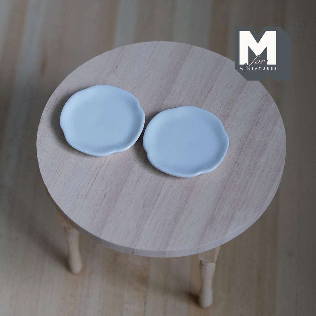 1:12 scale miniature light blue ceramic round plates, plain, set of 2, shown on a round wood table