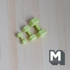 1:12 scale miniature metal hexagon dumbbells in light green, set of 3 graduated sizes, on a light wood surface
