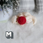 1:12 scale miniature resin cat in cream lying down playing with a red yarn ball, shown on a white fur rug