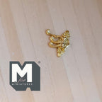 1:12 scale miniature gold metal plated triple coat hook with scroll detail, shown on a light wood surface