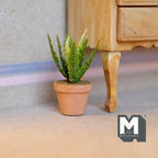 1:12 scale miniature potted succulent in a terracotta pot with spiky yellow edged leaves, shown beside a wood dresser leg