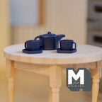 1:12 scale miniature metal pentagon teapot with cups and plates in dark blue, set of 5, on a round wood table