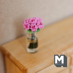 1:12 scale miniature pink roses in a clear glass vase with green stems, shown on a wood dresser