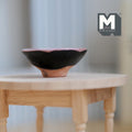 1:12 scale miniature large black clay fruit bowl with flared rim and terracotta foot, shown on a round wood table