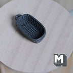 1:12 scale miniature rope weave bread basket in dark gray, oval with end handle, shown on a round wood table