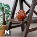 1:12 scale miniature clay owl shaped flower pot in brown and white with a feather pattern, on a dark wood shelf