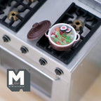 1:12 scale miniature vegetable soup in a brown metal pot with lid, shown on a stainless stove top