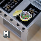 1:12 scale miniature vegetable soup in a yellow metal pot with lid, shown on a kitchen stove top