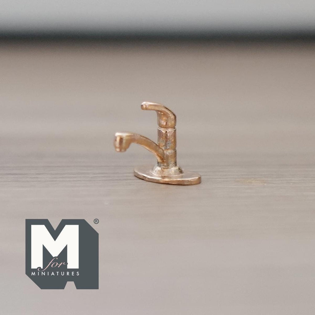 1:12 scale miniature metal single lever faucet in brass with a curved spout, shown on a wood surface
