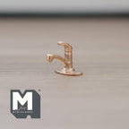 1:12 scale miniature metal single lever faucet in brass with a curved spout, shown on a wood surface