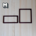 1:12 scale miniature metal photo frames in brown, set of 2, thin rectangular borders, shown on a light wood surface