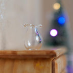 1:12 scale miniature clear glass pear shaped vase with ruffled rim, shown on a wood dresser with holiday lights behind