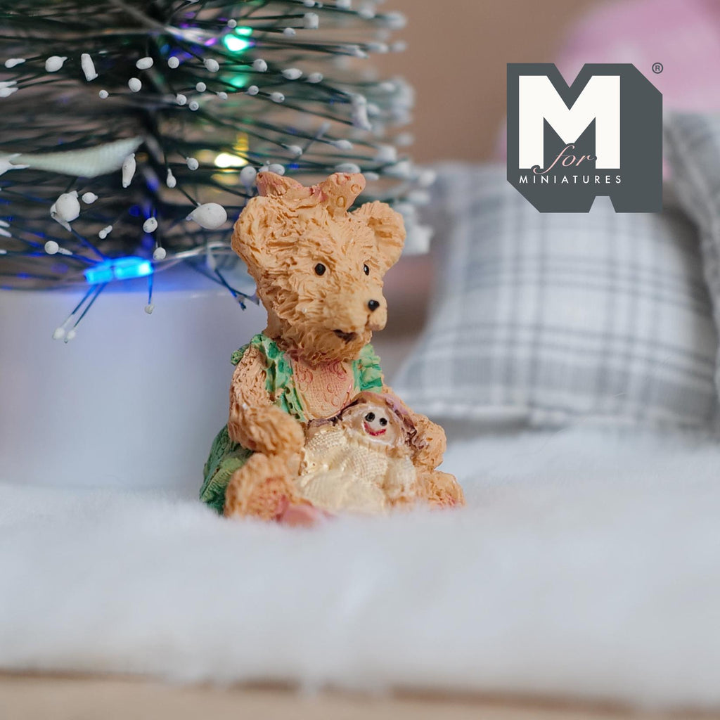 1:12 scale miniature resin bear figurine in a green dress holding a small girl doll, shown on a white fur rug
