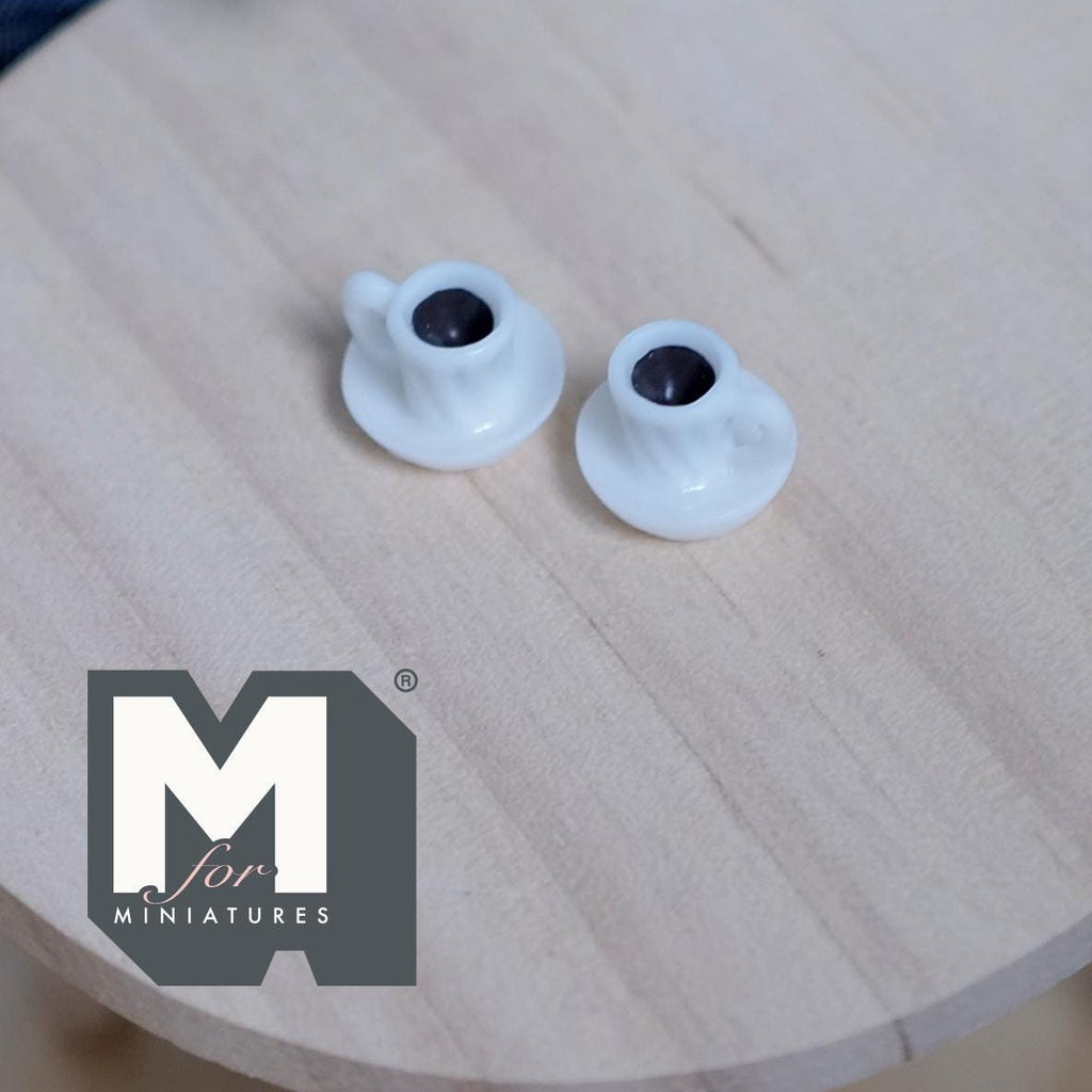 1:12 scale miniature white coffee mugs with attached saucers, set of 2, filled with dark coffee, on a round wood table