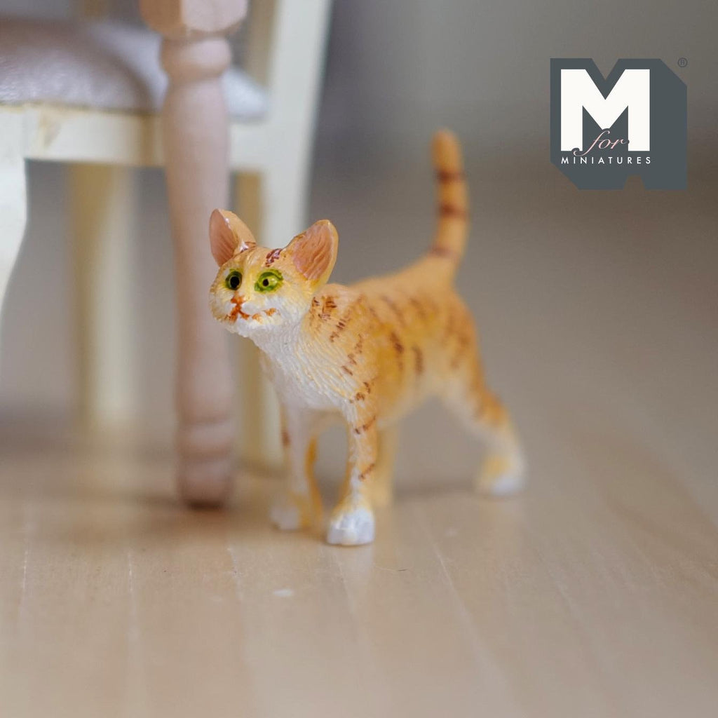 1:12 scale miniature cast resin standing ginger tabby cat with striped tail up, shown on a wood floor by a chair