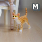1:12 scale miniature cast resin standing ginger tabby cat with striped tail up, shown on a wood floor by a chair